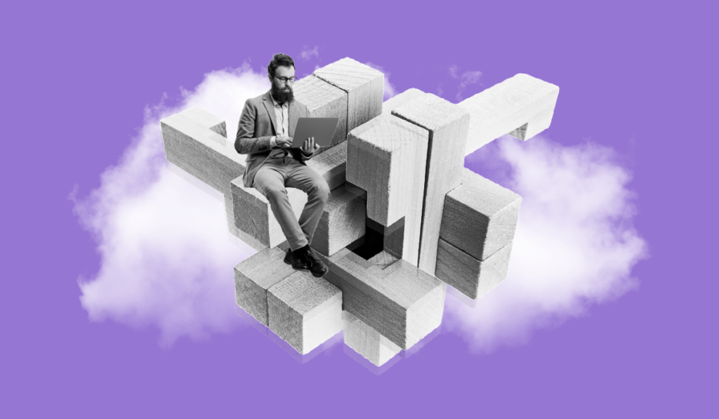 Man in suit holding a laptop and developing his HR strategy while sitting on a giant wooden puzzle amidst a background of clouds